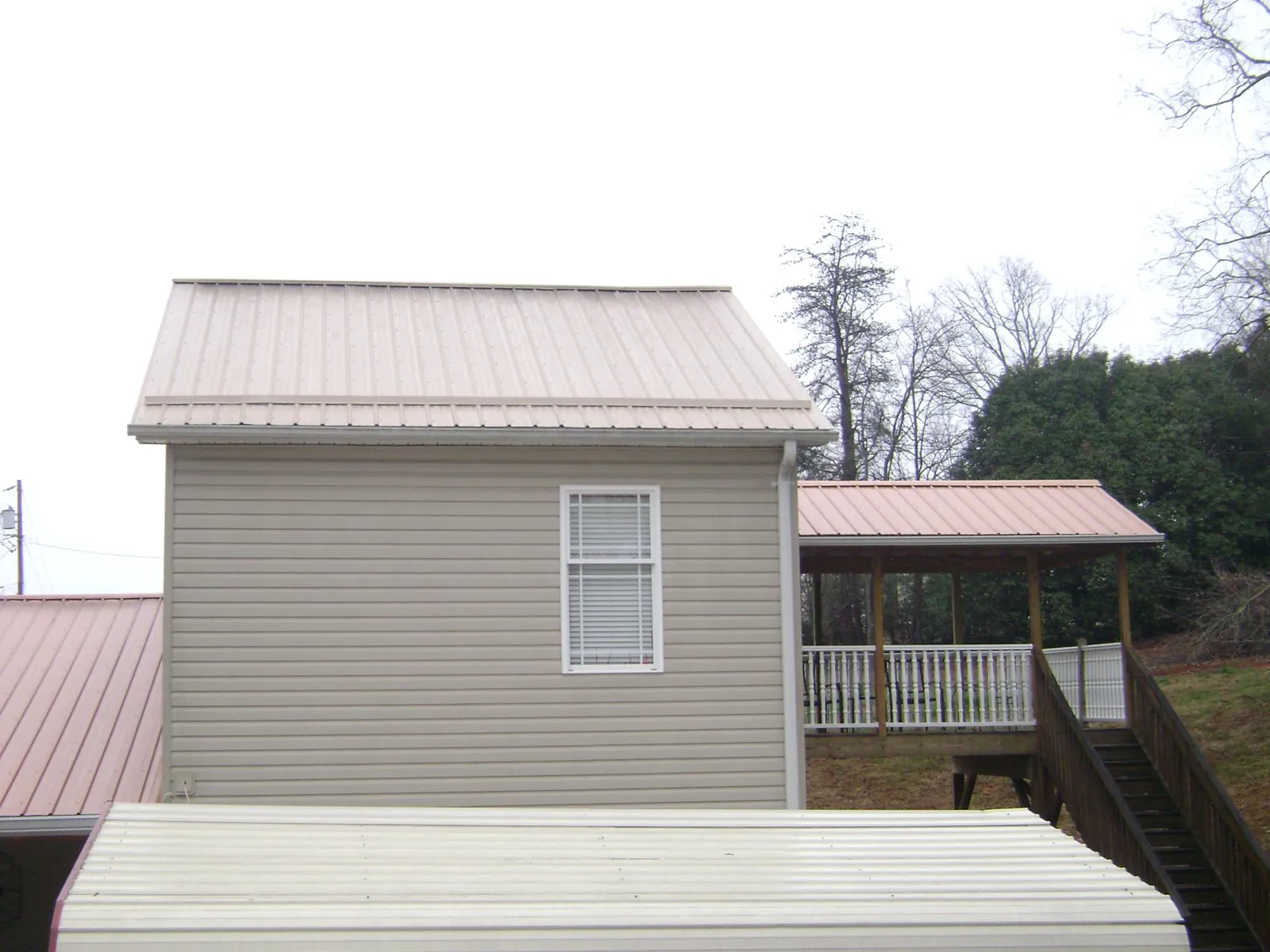 Tan metal roofs on a two story addition and attached porch, from a Roof Replacement job in Dale