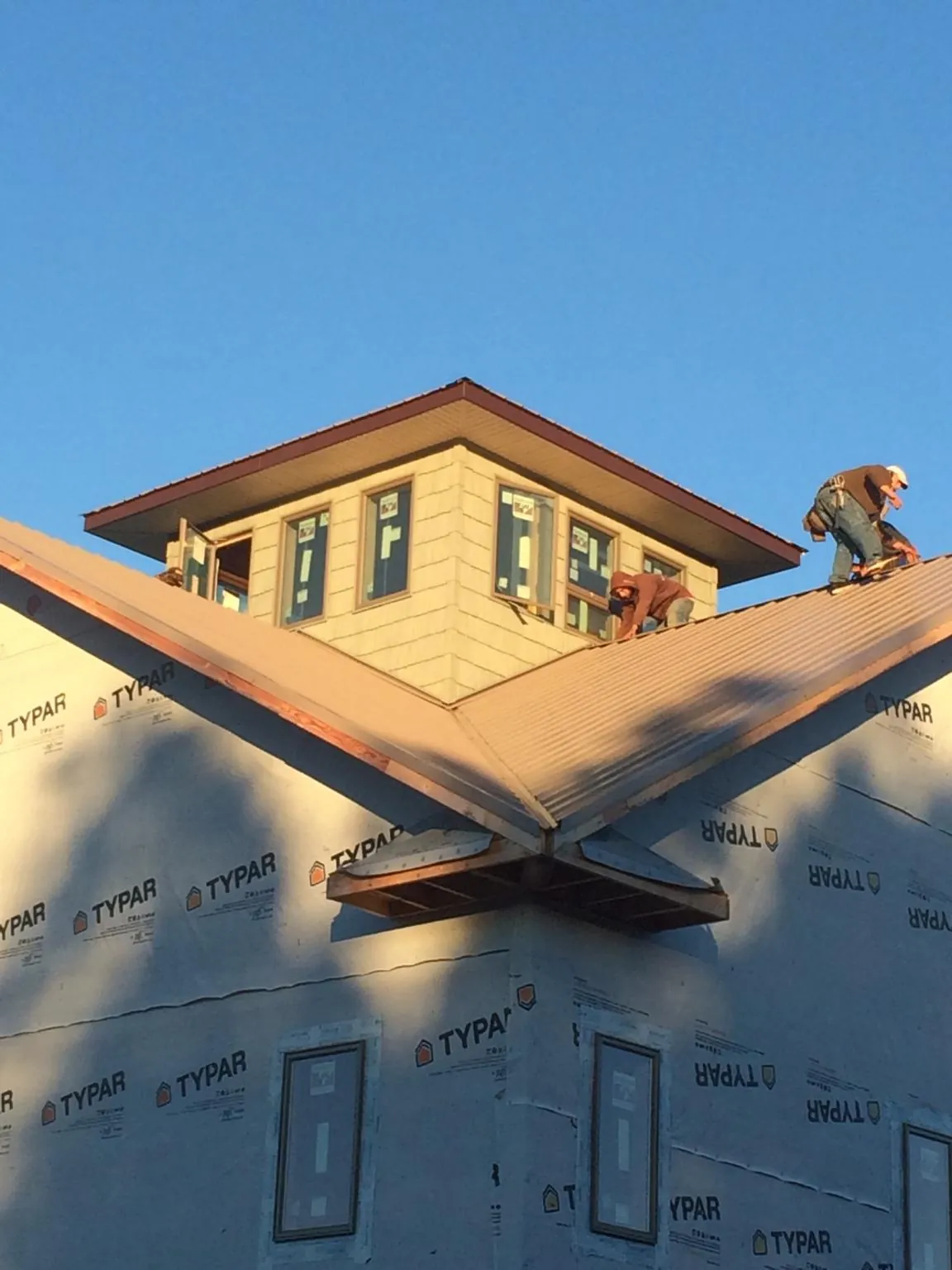 Roofers working around a rooftop cupola on a new metal roof at sunset — Roof Waterproofing in Dale by Roofing Brothers